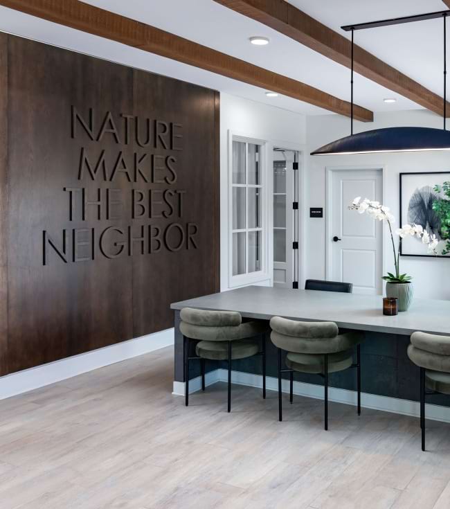 Leasing office with large desk and chairs, and wall decor that says Nature Makes The Best Neighbor Leasing office with large desk and chairs, and wall decor that says Nature Makes The Best Neighbor